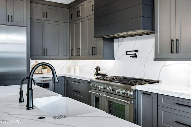 kitchen with a sink, gray cabinets, custom exhaust hood, and high quality appliances