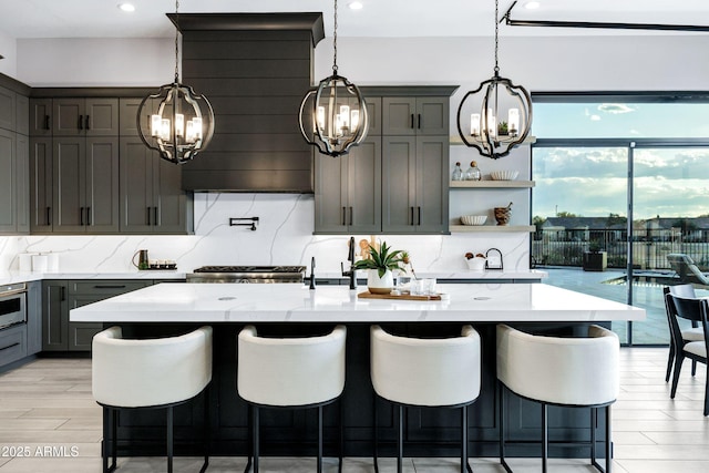kitchen featuring an inviting chandelier, a breakfast bar, gray cabinetry, and tasteful backsplash