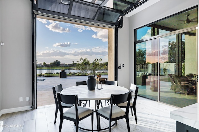 dining room featuring a water view and baseboards
