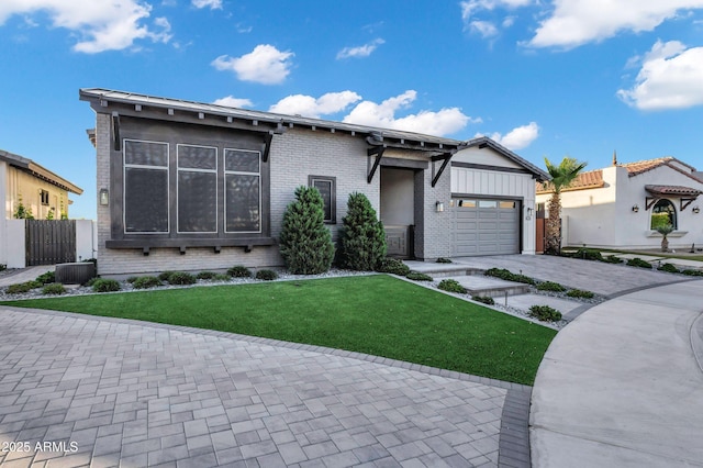 view of front of house featuring fence, a front yard, brick siding, an attached garage, and driveway