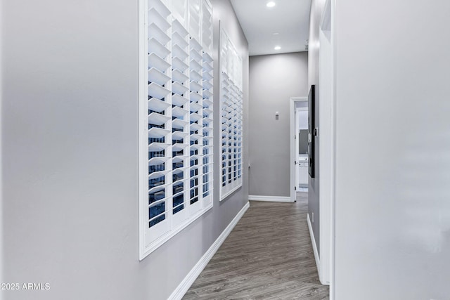 hallway featuring baseboards, recessed lighting, and wood finished floors