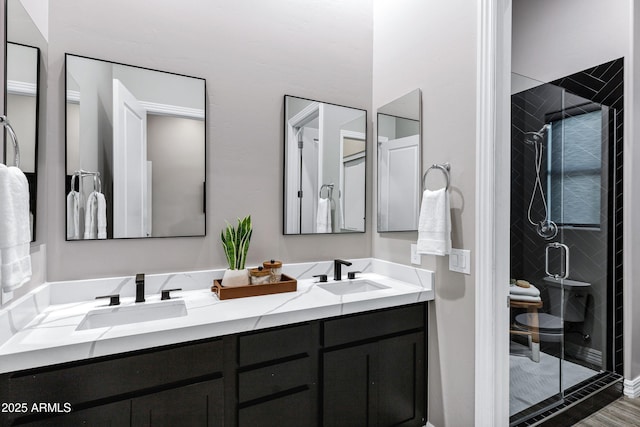 bathroom with double vanity, a shower stall, and a sink