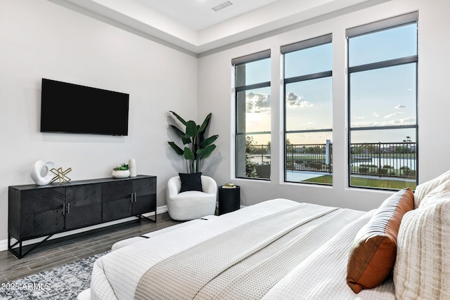 bedroom with baseboards, visible vents, and wood finished floors