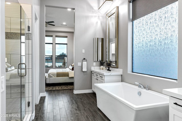 bathroom with vanity, wood finished floors, baseboards, ceiling fan, and a stall shower