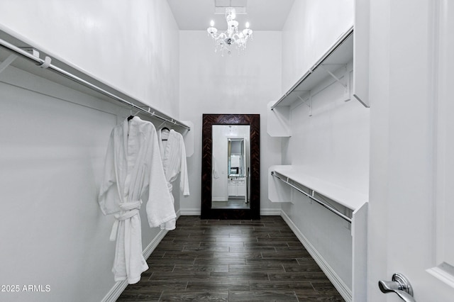 walk in closet featuring dark wood finished floors and a chandelier