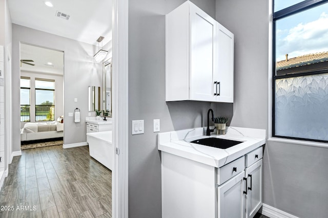 washroom with visible vents, wood finished floors, baseboards, recessed lighting, and a sink