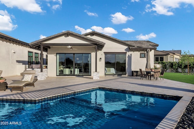 back of house with a patio, a ceiling fan, an outdoor pool, and stucco siding