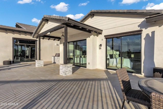 back of property with a ceiling fan, stucco siding, and a patio area