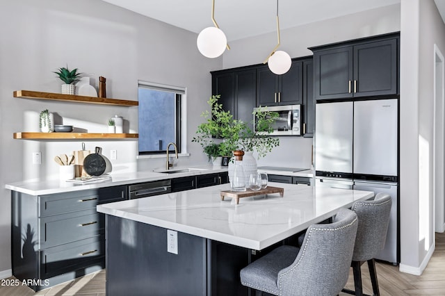 kitchen featuring a kitchen island, appliances with stainless steel finishes, a sink, light stone counters, and a breakfast bar