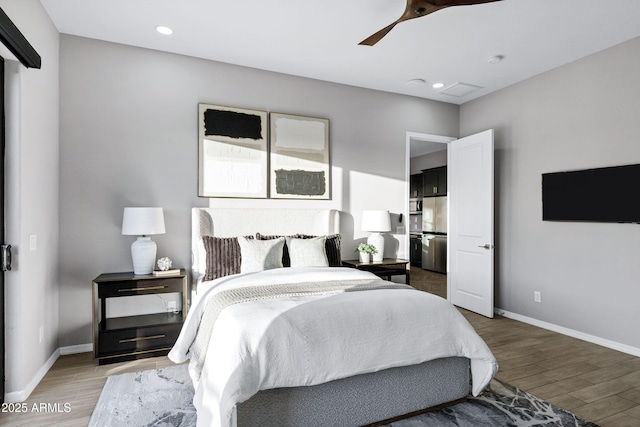 bedroom featuring freestanding refrigerator, baseboards, and light wood-style floors