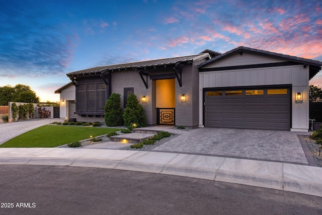 view of front facade with an attached garage, decorative driveway, a lawn, and brick siding