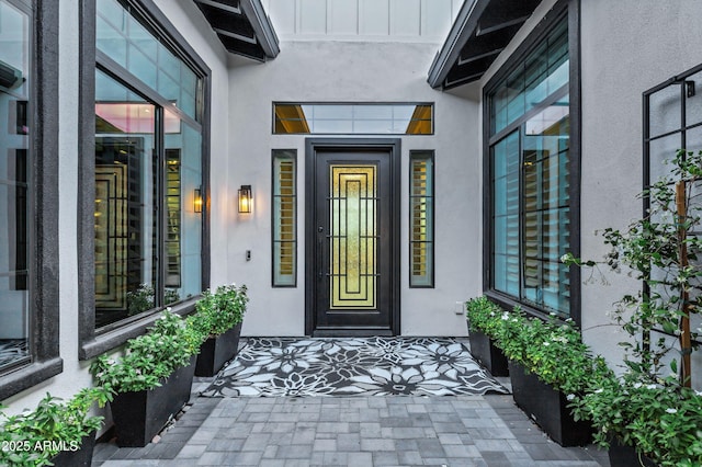 view of exterior entry featuring board and batten siding and stucco siding
