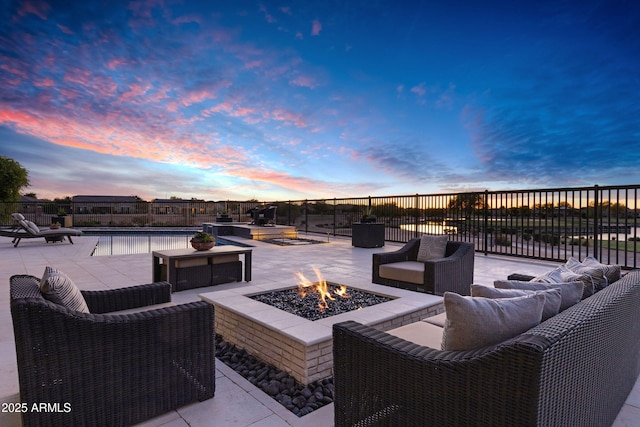 patio terrace at dusk featuring a fenced in pool and an outdoor living space with a fire pit