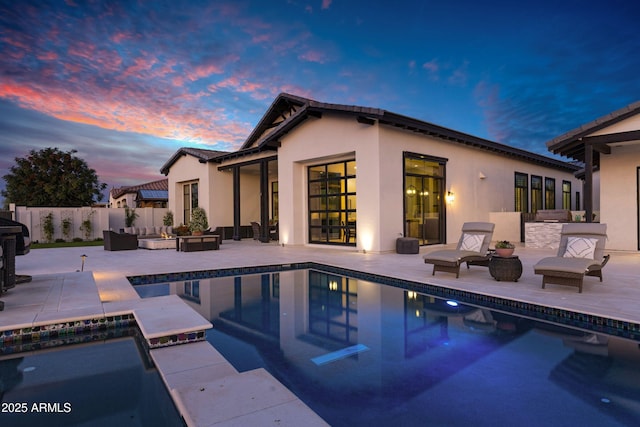 exterior space with a fenced in pool, stucco siding, an outdoor living space, and a patio area