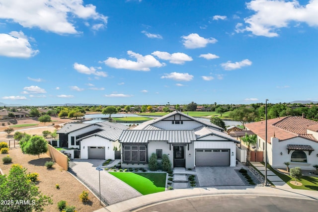 view of front of home with fence, an attached garage, driveway, and metal roof