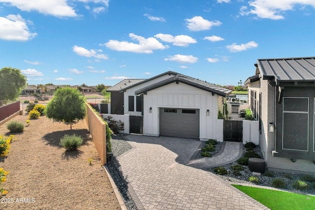 view of front of home featuring fence, an attached garage, board and batten siding, a gate, and decorative driveway