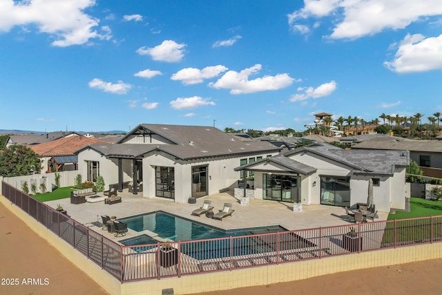 back of house featuring a pool with connected hot tub, a patio area, a fenced backyard, outdoor lounge area, and stucco siding