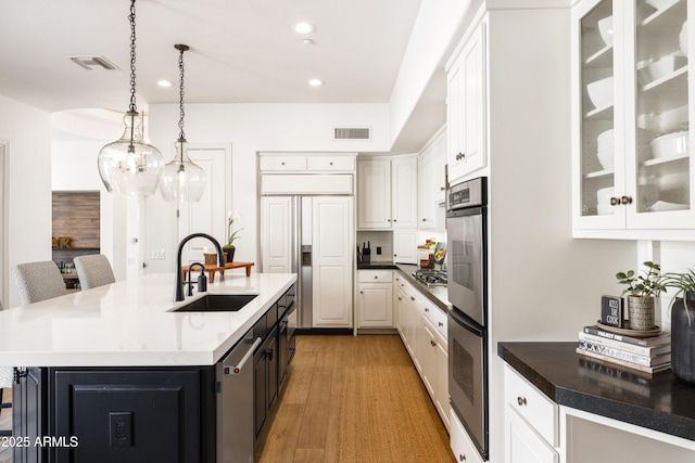 kitchen featuring visible vents, light wood-type flooring, stainless steel gas stovetop, white cabinetry, and a sink