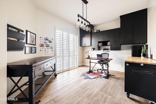 kitchen with black dishwasher, decorative light fixtures, butcher block countertops, light wood-type flooring, and dark cabinetry