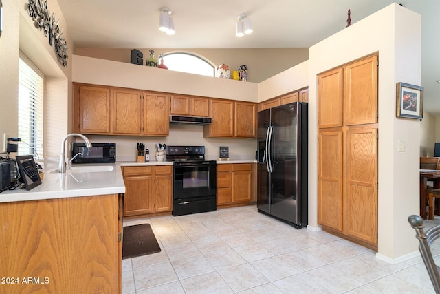 kitchen featuring light tile patterned floors, sink, lofted ceiling, and black appliances