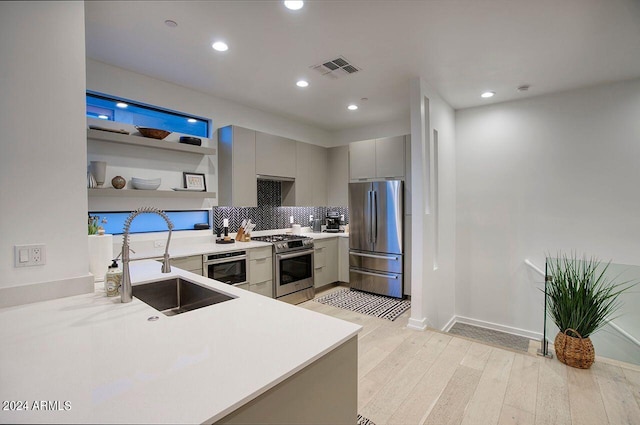 kitchen featuring gray cabinetry, a sink, open shelves, appliances with stainless steel finishes, and light wood finished floors