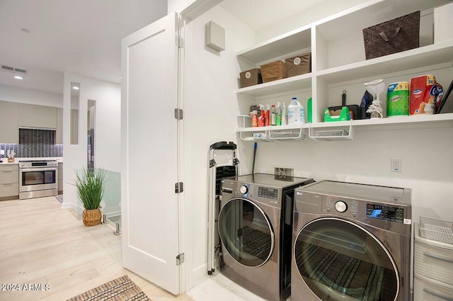 laundry area with visible vents, washing machine and dryer, laundry area, and light wood-style floors