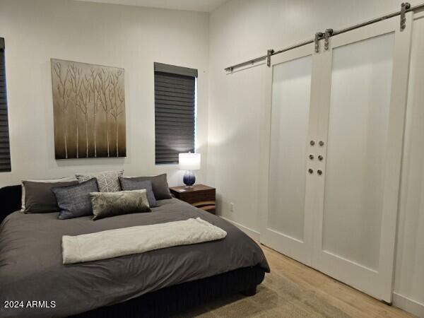 bedroom with a barn door and light hardwood / wood-style floors