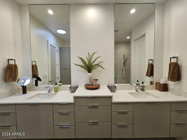 bathroom with a tile shower and vanity