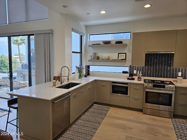 kitchen with kitchen peninsula, sink, a breakfast bar, appliances with stainless steel finishes, and light hardwood / wood-style floors