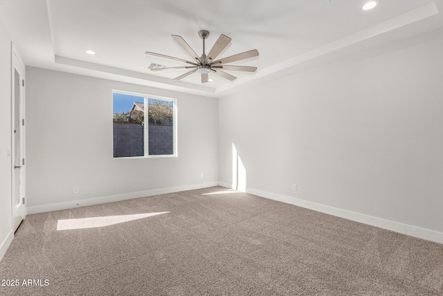 spare room with ceiling fan, carpet, and a tray ceiling