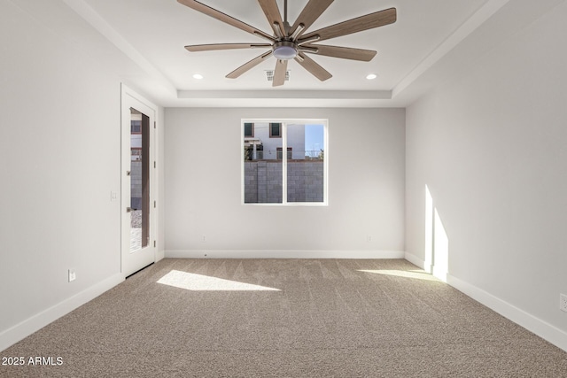 carpeted empty room with ceiling fan and a tray ceiling