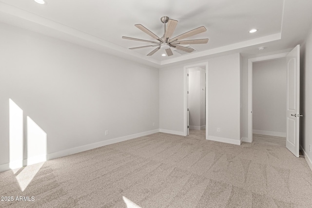 unfurnished bedroom featuring a raised ceiling, light colored carpet, ceiling fan, and a closet