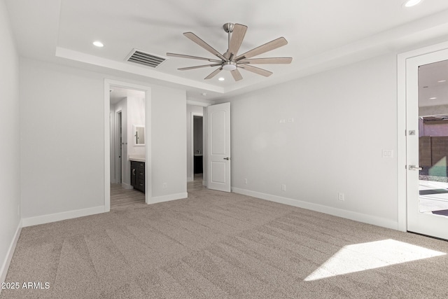 unfurnished bedroom featuring ceiling fan, light colored carpet, and a tray ceiling