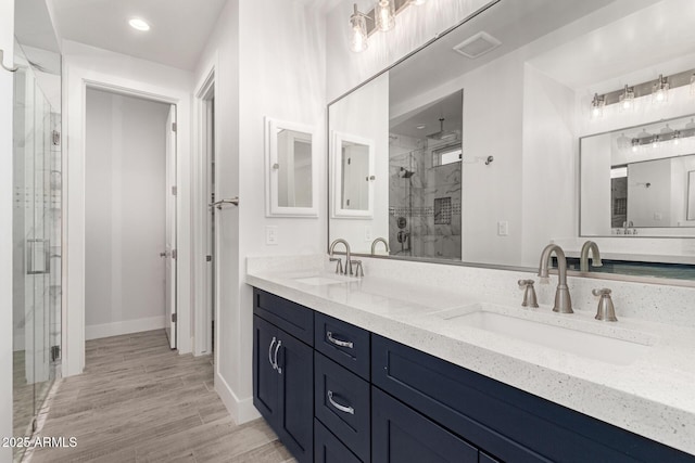 bathroom featuring a shower with door and vanity