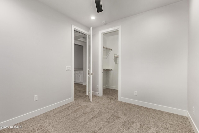 unfurnished bedroom with ceiling fan, a walk in closet, a closet, and carpet floors