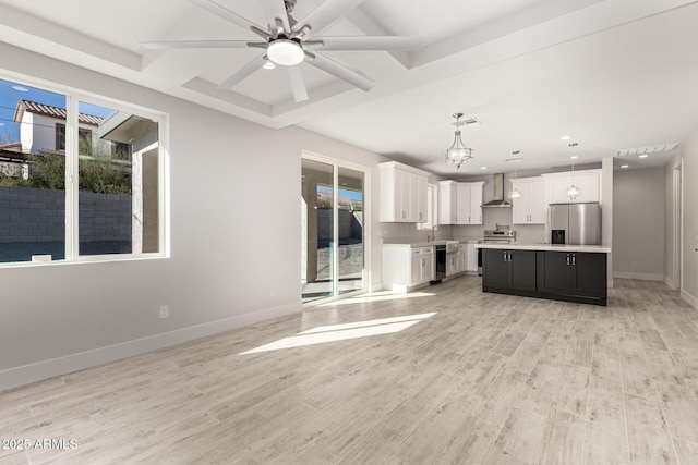 kitchen with appliances with stainless steel finishes, a center island, pendant lighting, wall chimney exhaust hood, and white cabinetry