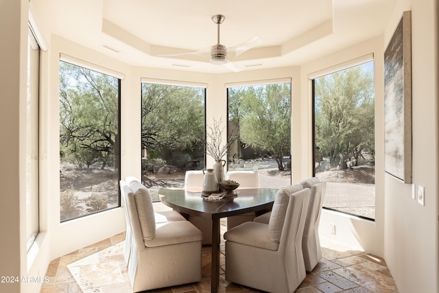 dining area featuring a tray ceiling, ceiling fan, and plenty of natural light