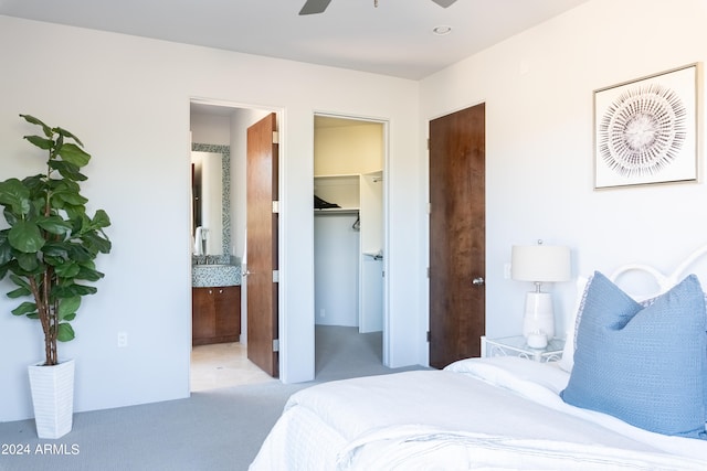 carpeted bedroom with ceiling fan, a walk in closet, and ensuite bathroom