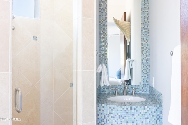 bathroom with backsplash, an enclosed shower, and sink