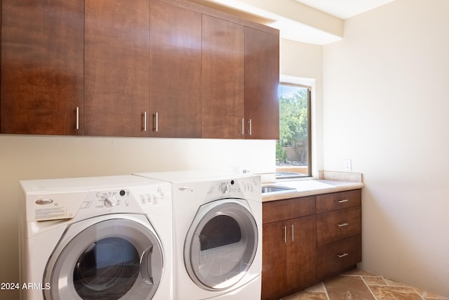 clothes washing area with washing machine and dryer and cabinets