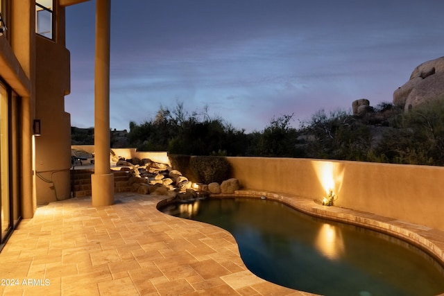 pool at dusk featuring a patio area