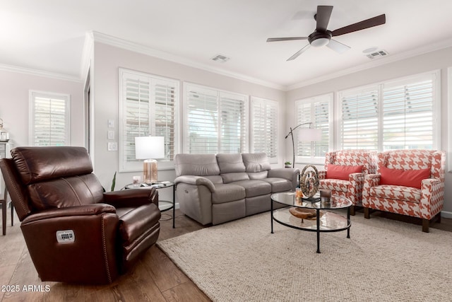 living room with a healthy amount of sunlight, visible vents, and ornamental molding