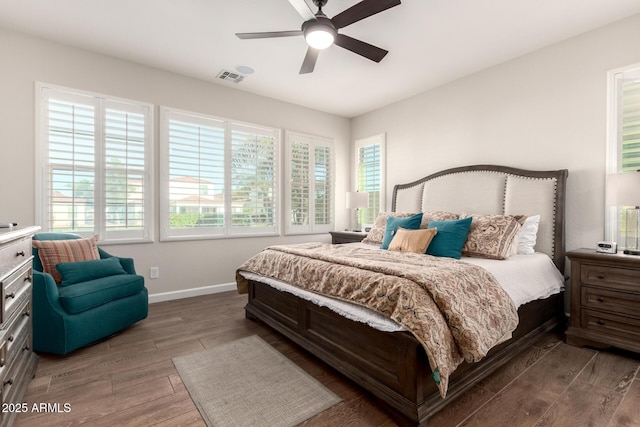 bedroom with ceiling fan, visible vents, baseboards, and wood finished floors