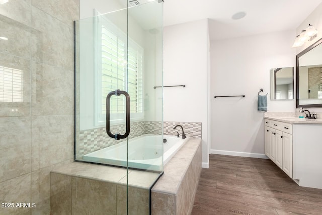 full bath with wood finished floors, a shower stall, baseboards, a bath, and vanity