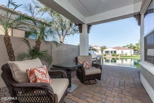 view of patio featuring fence and a water view