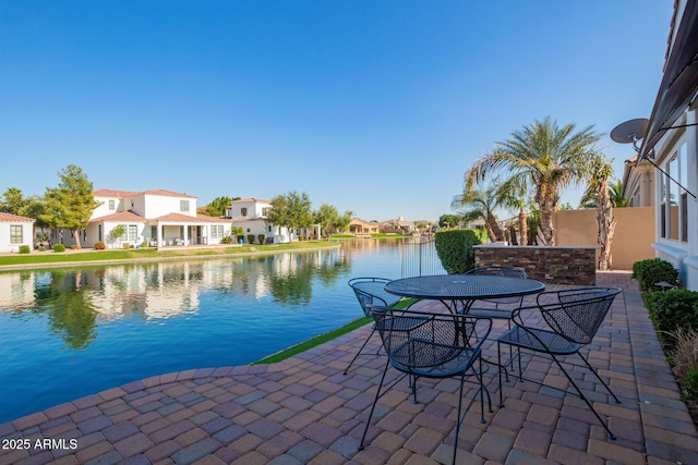 view of patio with a residential view, outdoor dining area, and a water view