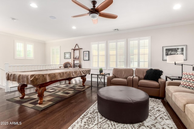 rec room featuring visible vents, dark wood-type flooring, crown molding, baseboards, and ceiling fan