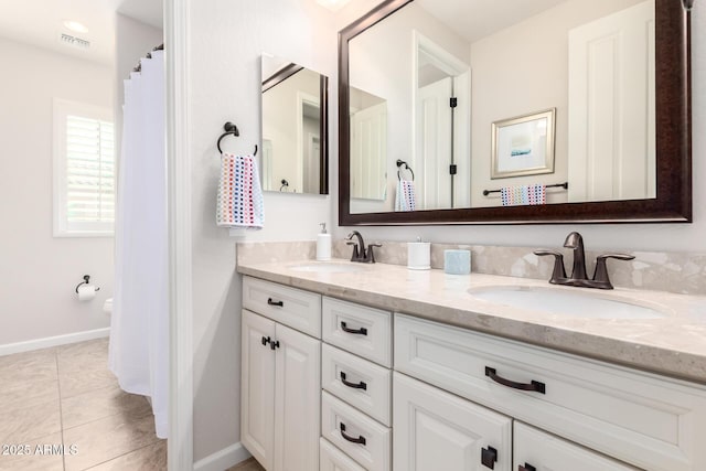 bathroom featuring tile patterned floors, double vanity, visible vents, and a sink