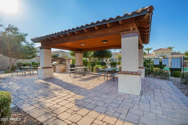 view of patio featuring a gazebo, outdoor dining space, an outdoor kitchen, and fence