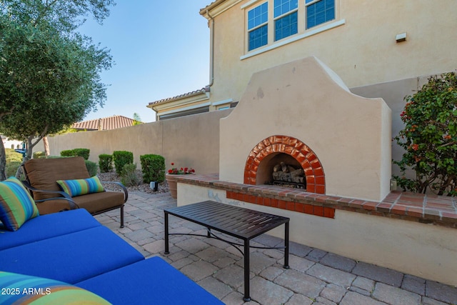 view of patio featuring an outdoor brick fireplace and fence